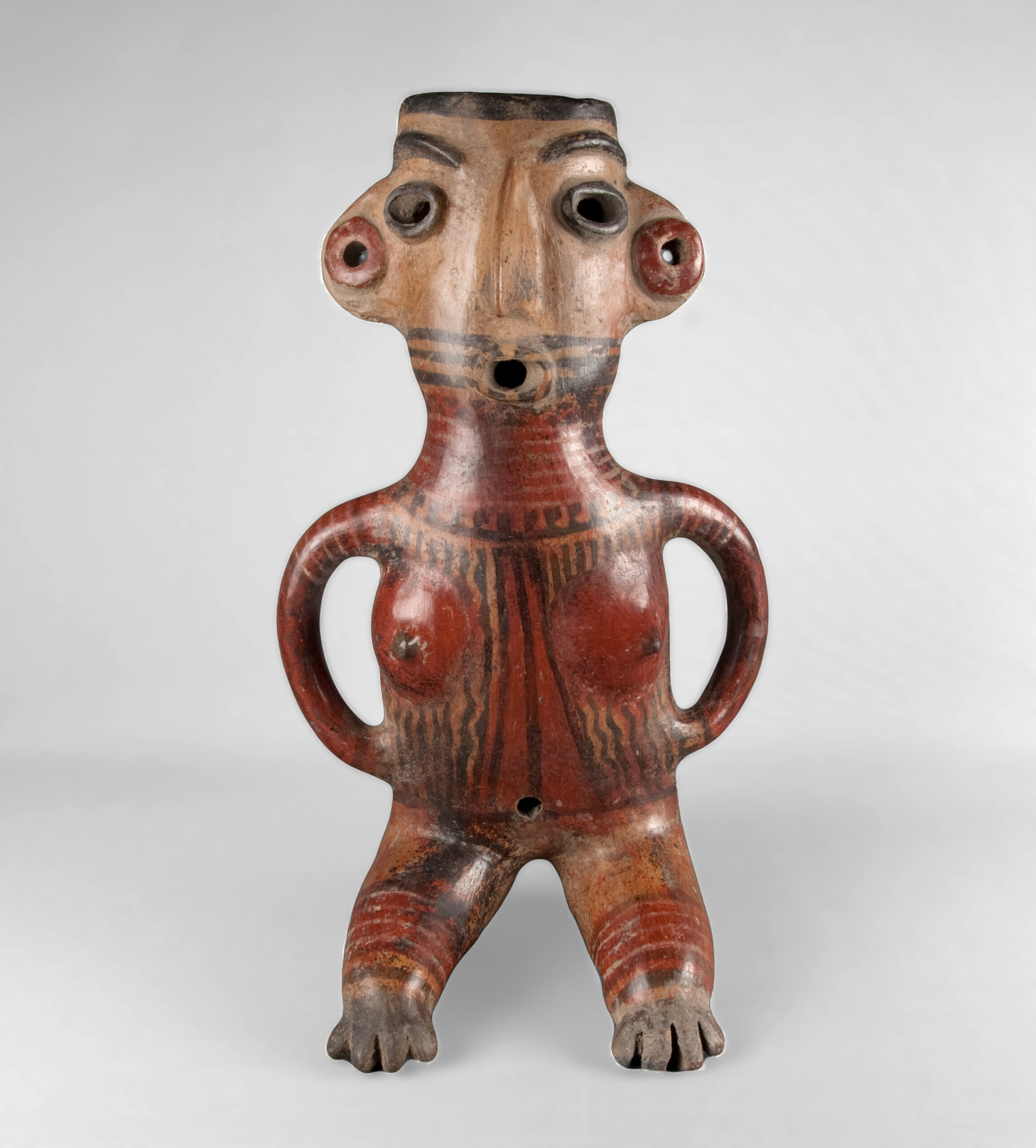 Stylized sculpture depicting a seated woman with hands on her hips, an open mouth, ear spools, and body paint.