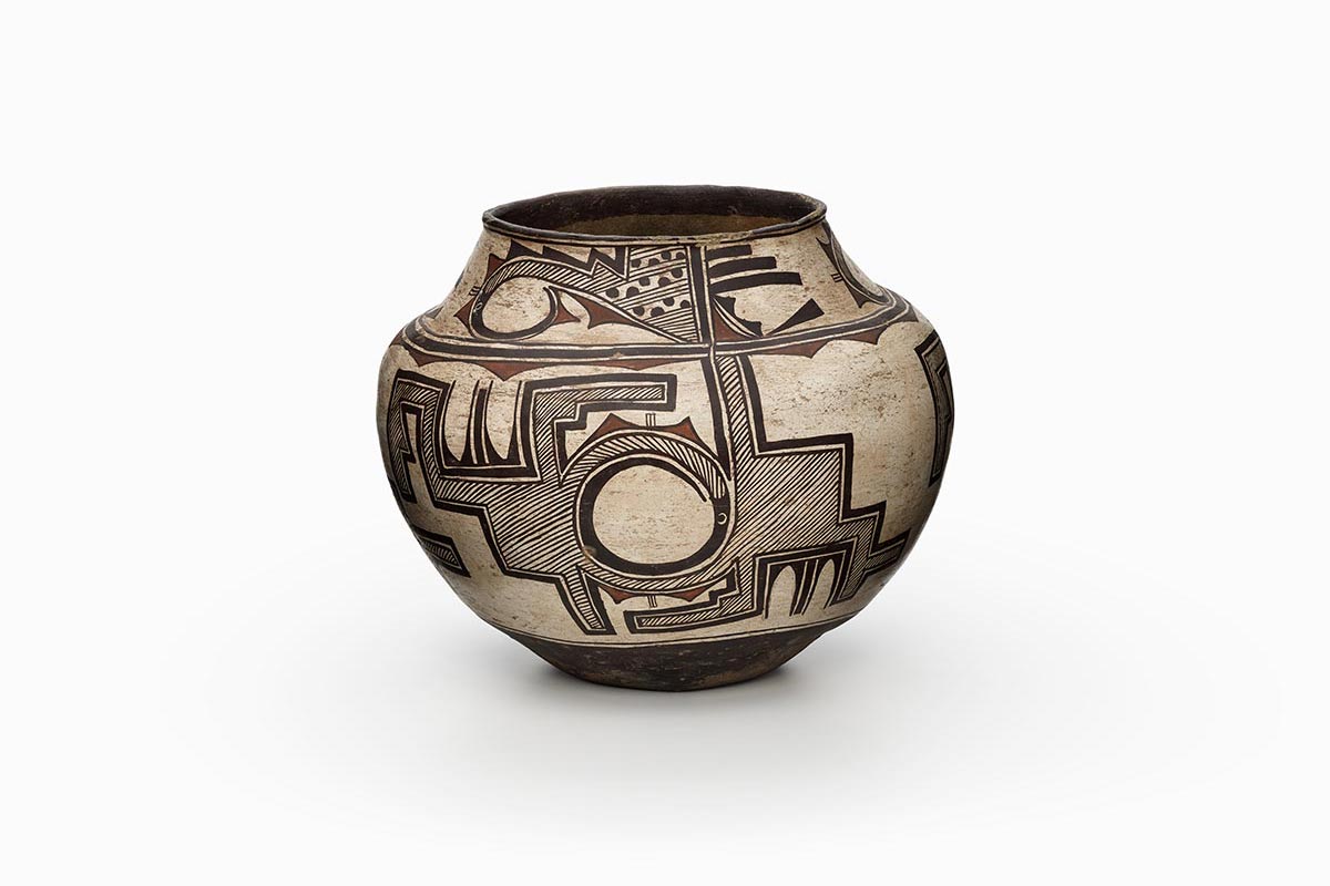 A three-color Zuni polychrome olla (water jar) features white slip with black and red painted decoration.