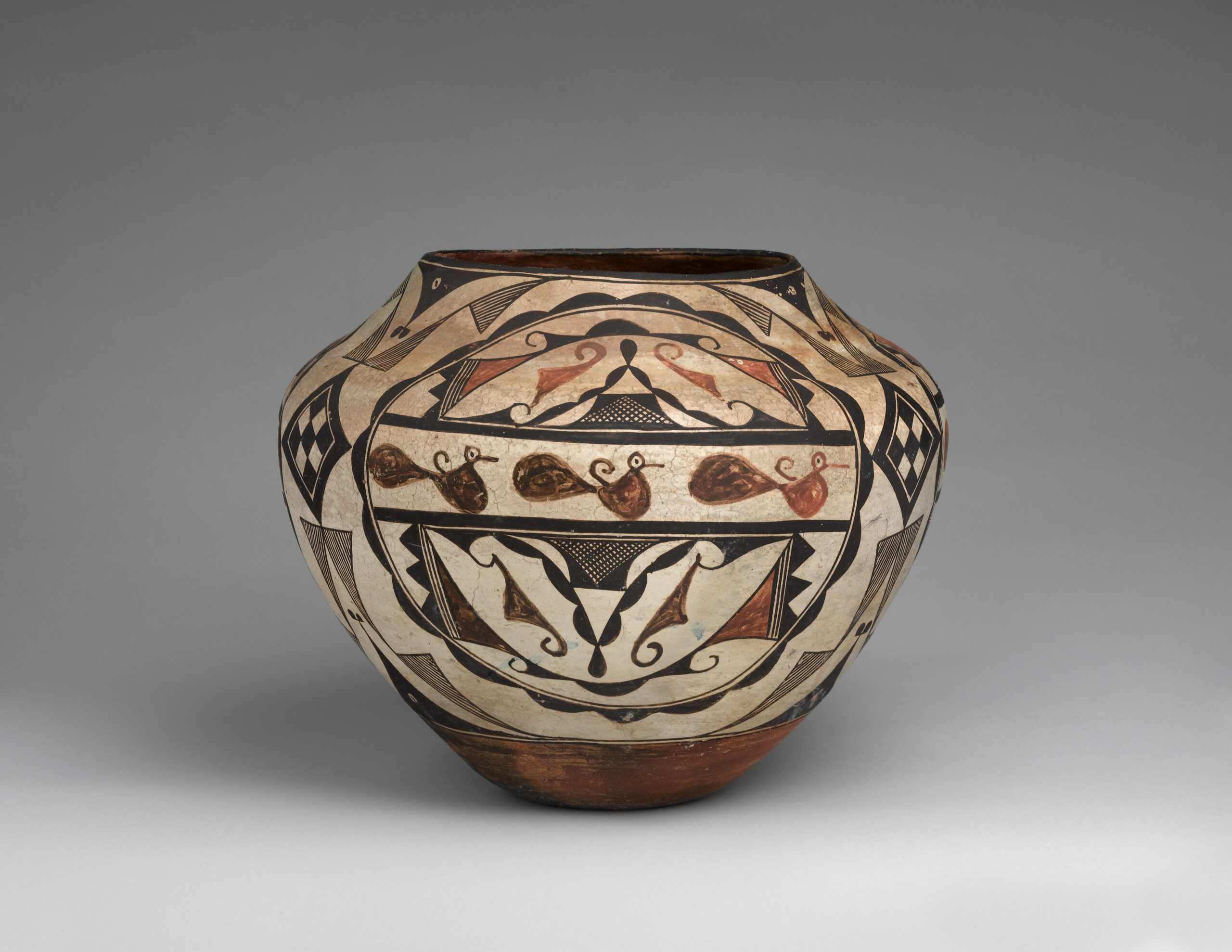 Beige Acoma pot with various geometric shapes and patterns in brown and black, and a row of three identical animals in the center.