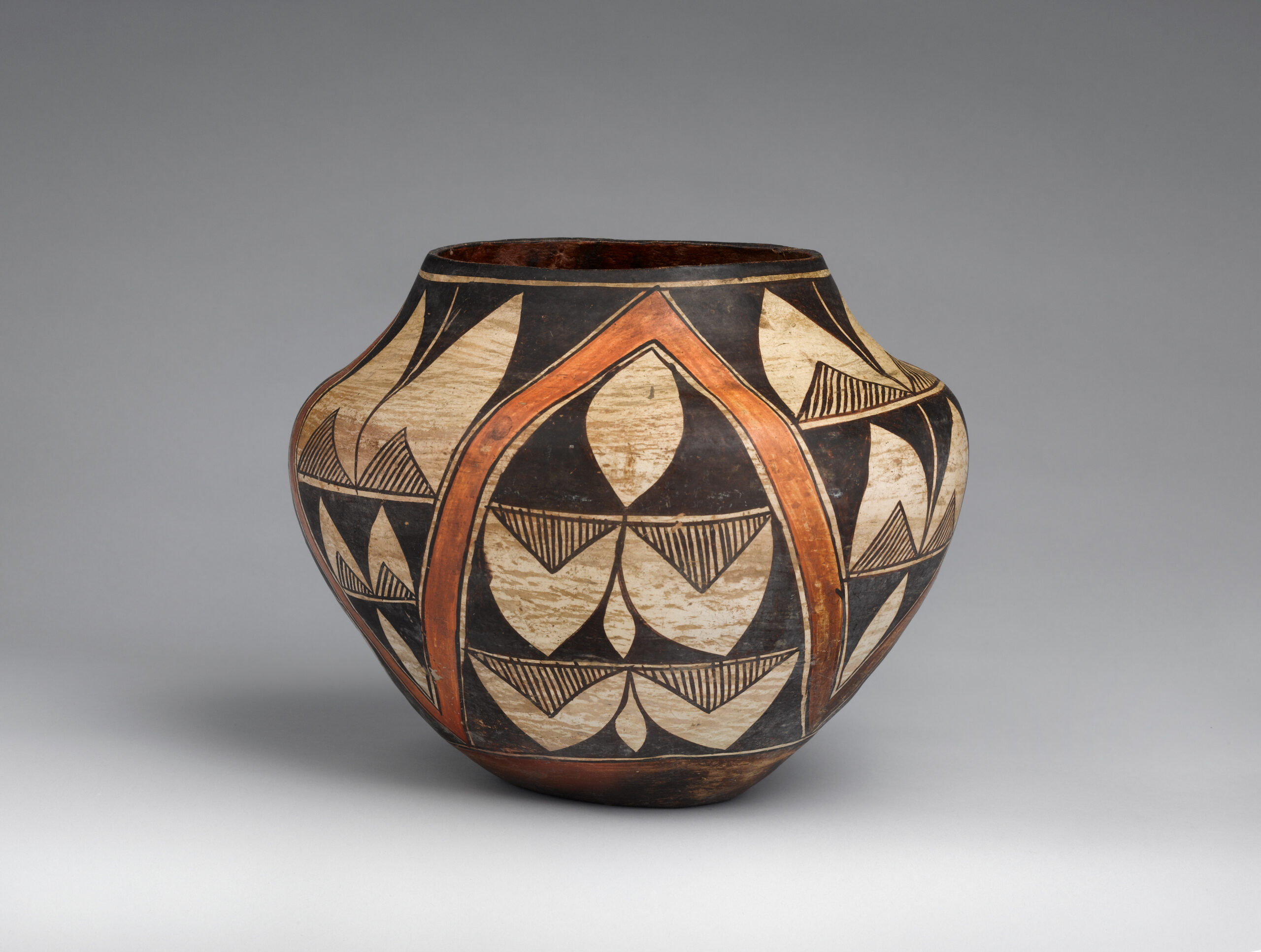 A small Acoma pot with a design primarily composed of lines and triangular shapes.