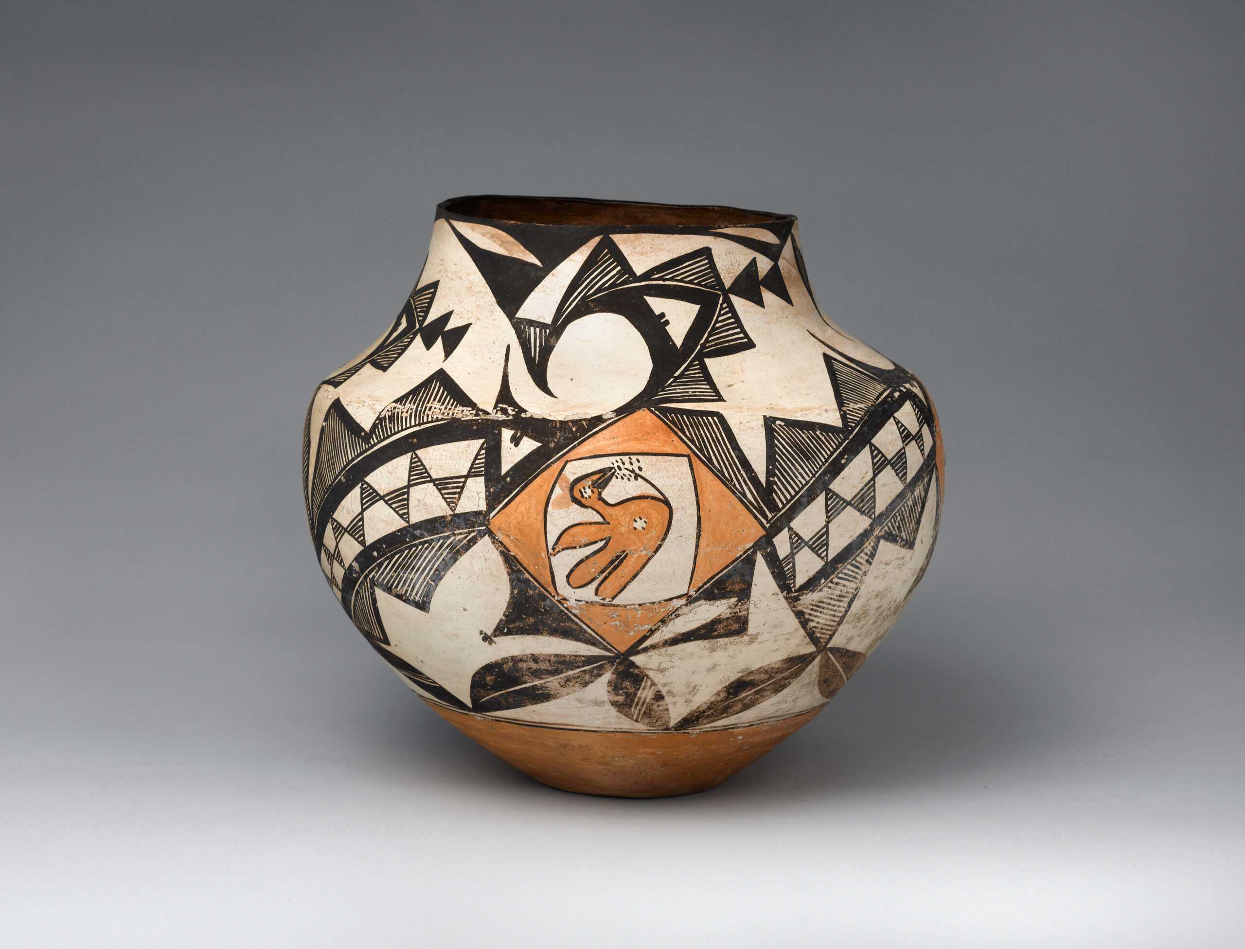 An Acoma jar decorated with a yellow bird and abstract geometric shapes and lines in black, white, and yellow.