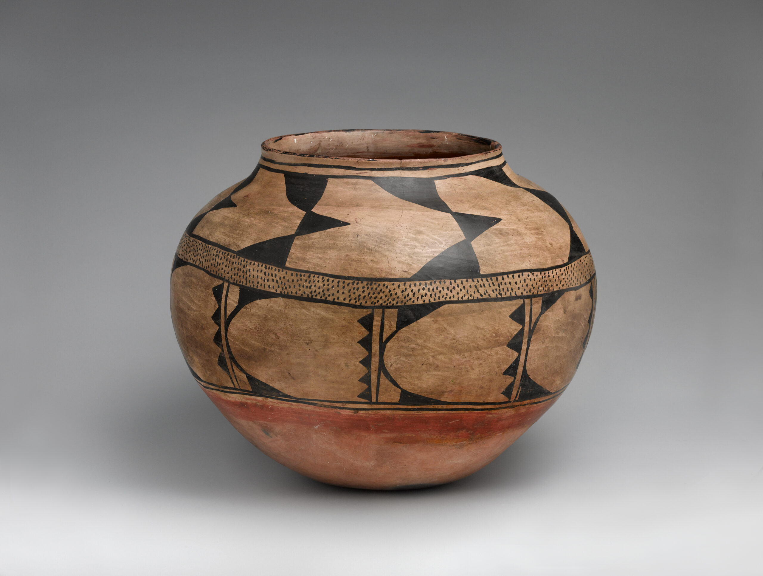 A Kewa storage jar, primarily painted brown, with a rust-orange bottom and black design.