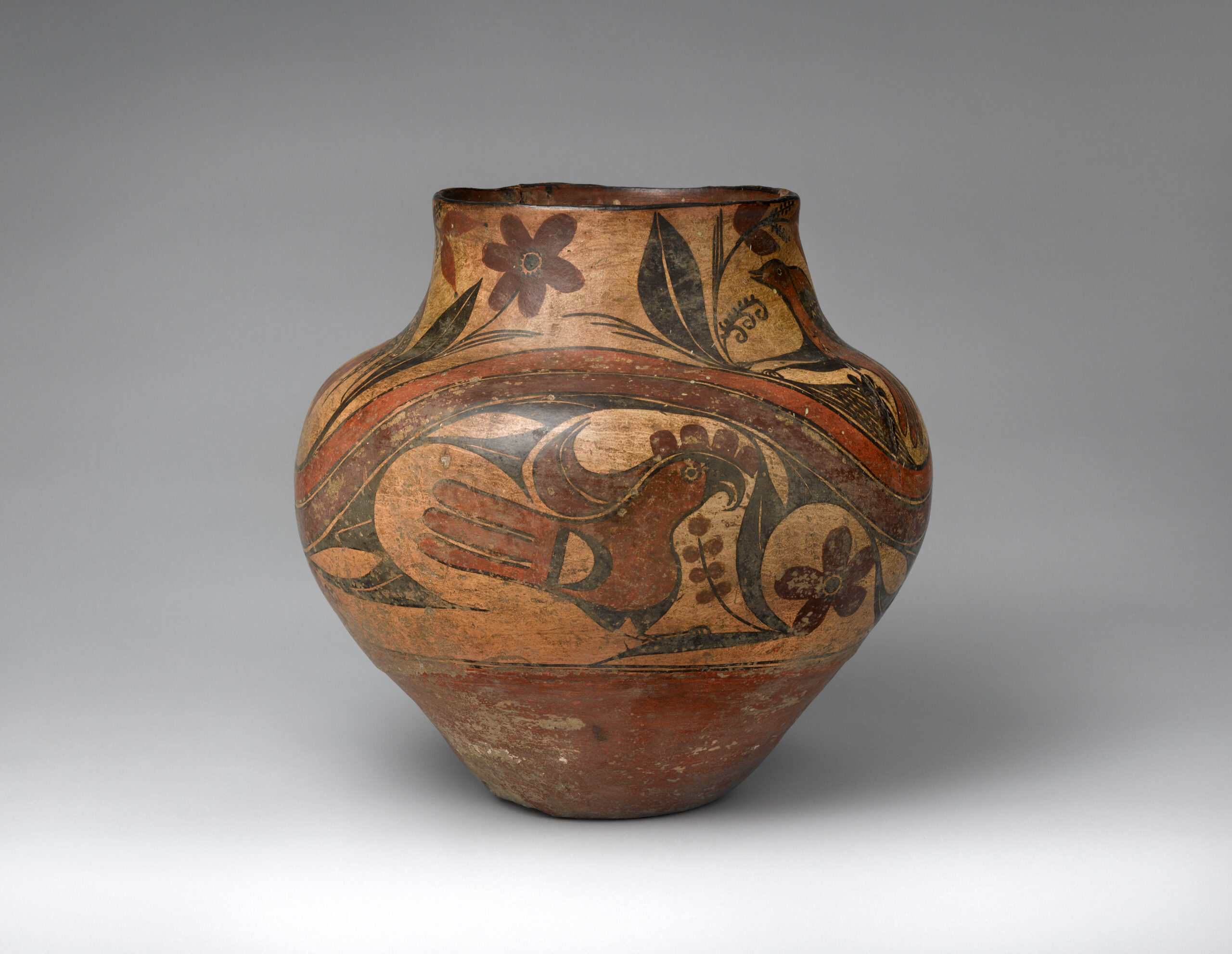 An Acoma polychrome olla decorated with birds and flora in black, browns, and rust.