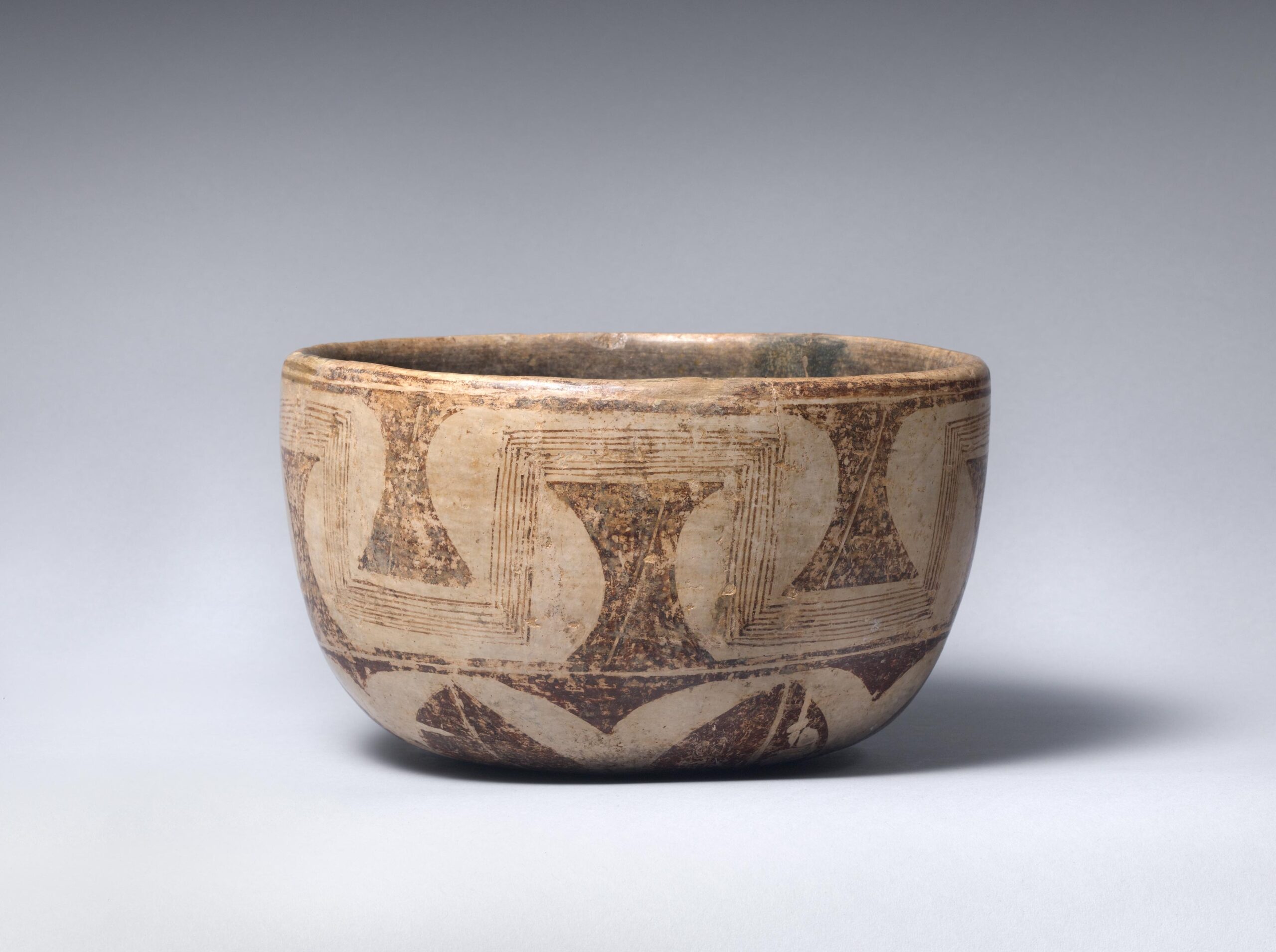 Ceramic bowl painted with striped, floral, and wedge motifs.