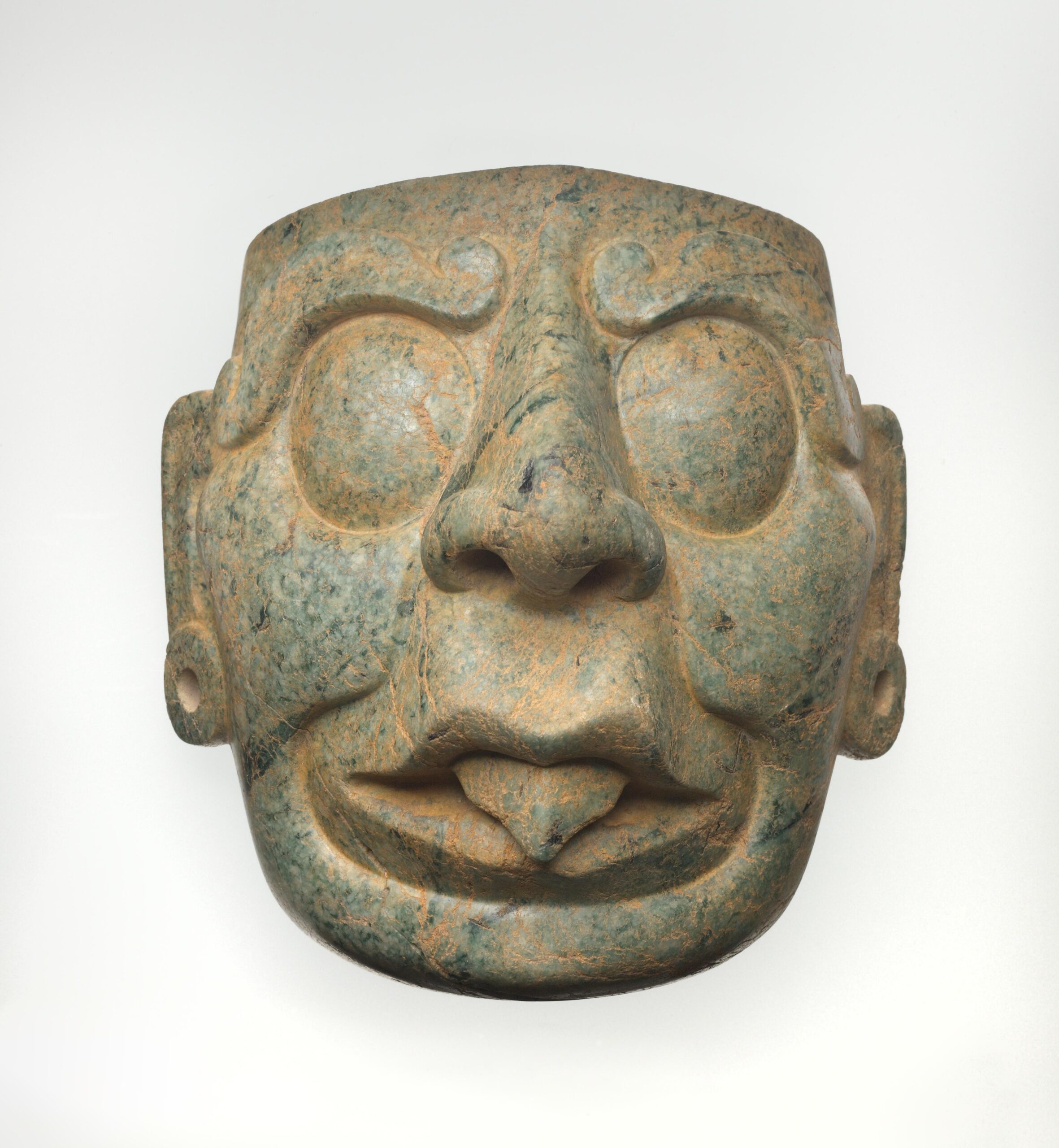 Face mask with large eyes, a prominent nose, open mouth, ear spools, and extended tongue.