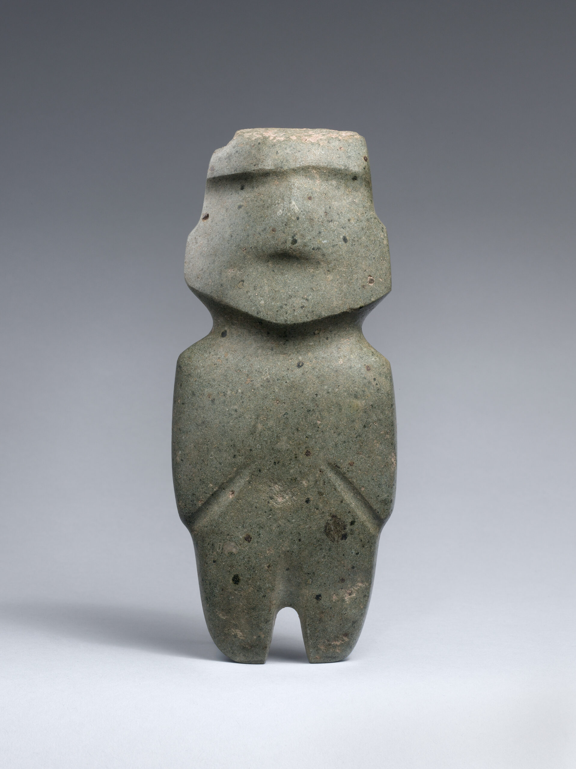 Small abstract stone carving of a standing human figure.