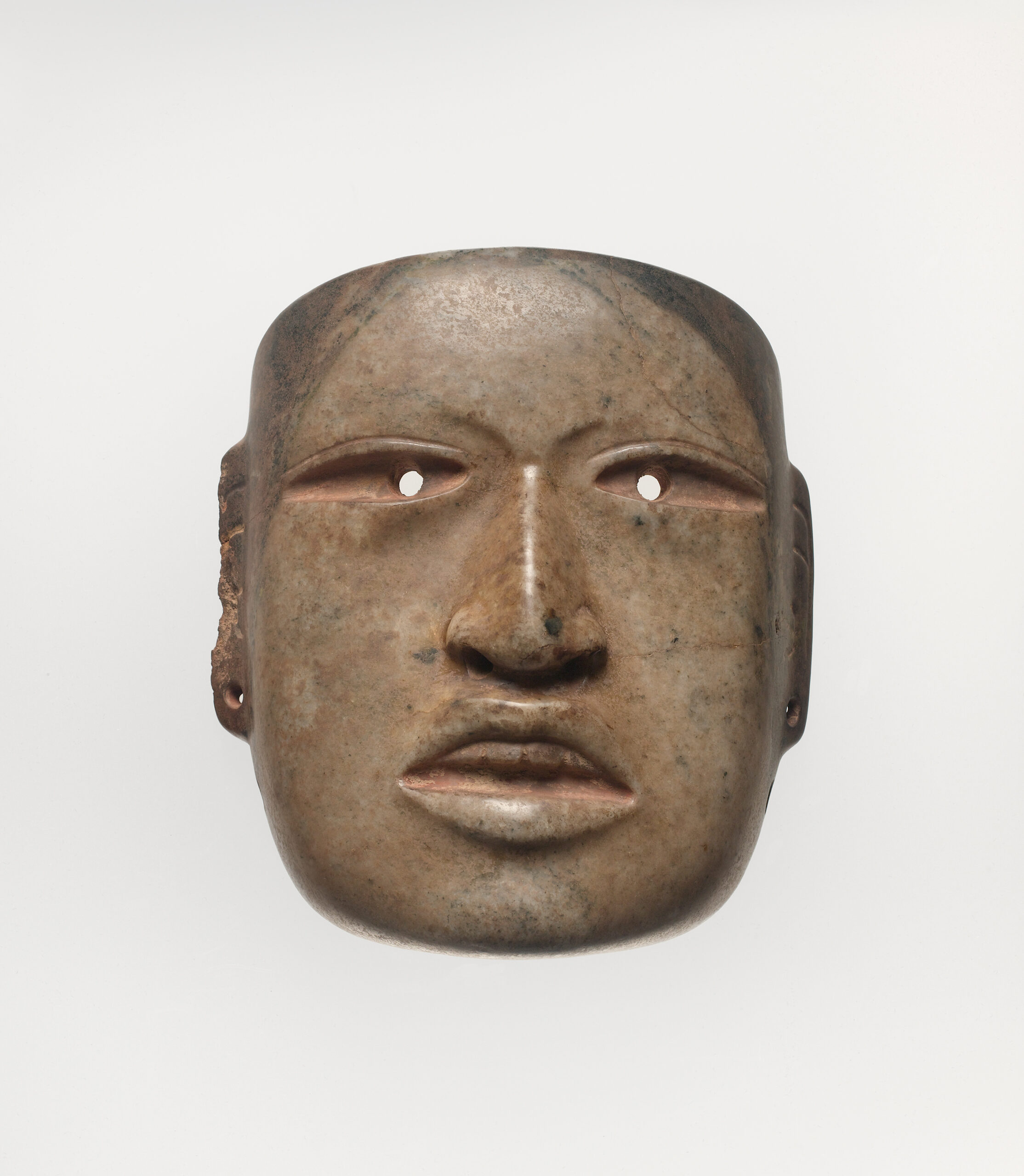 Ritualistic face mask with drilled eyes and ear spools, and a naturalistic mouth open to expose top teeth.