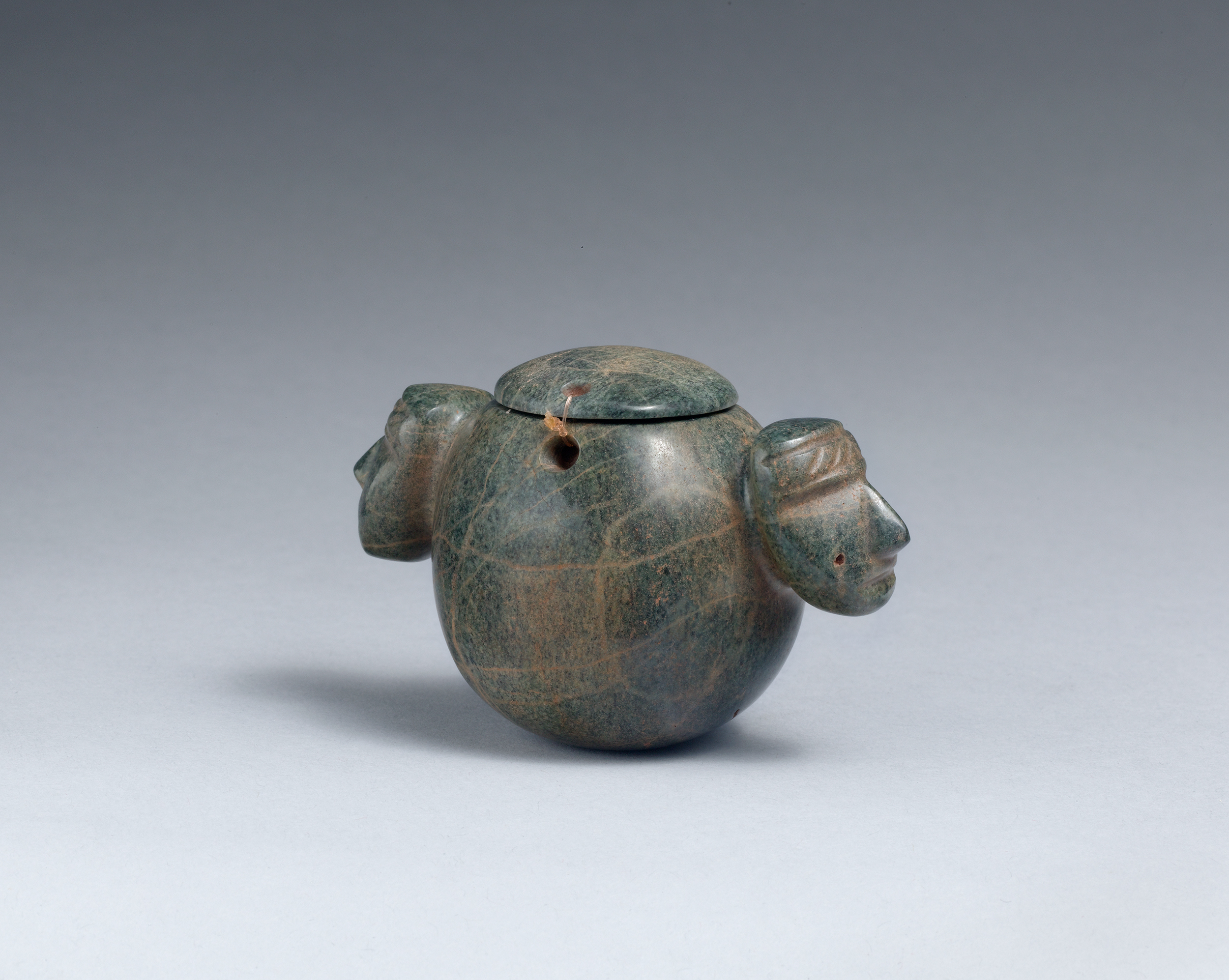 Vessel with stylized relief of two identical human heads on either side.
