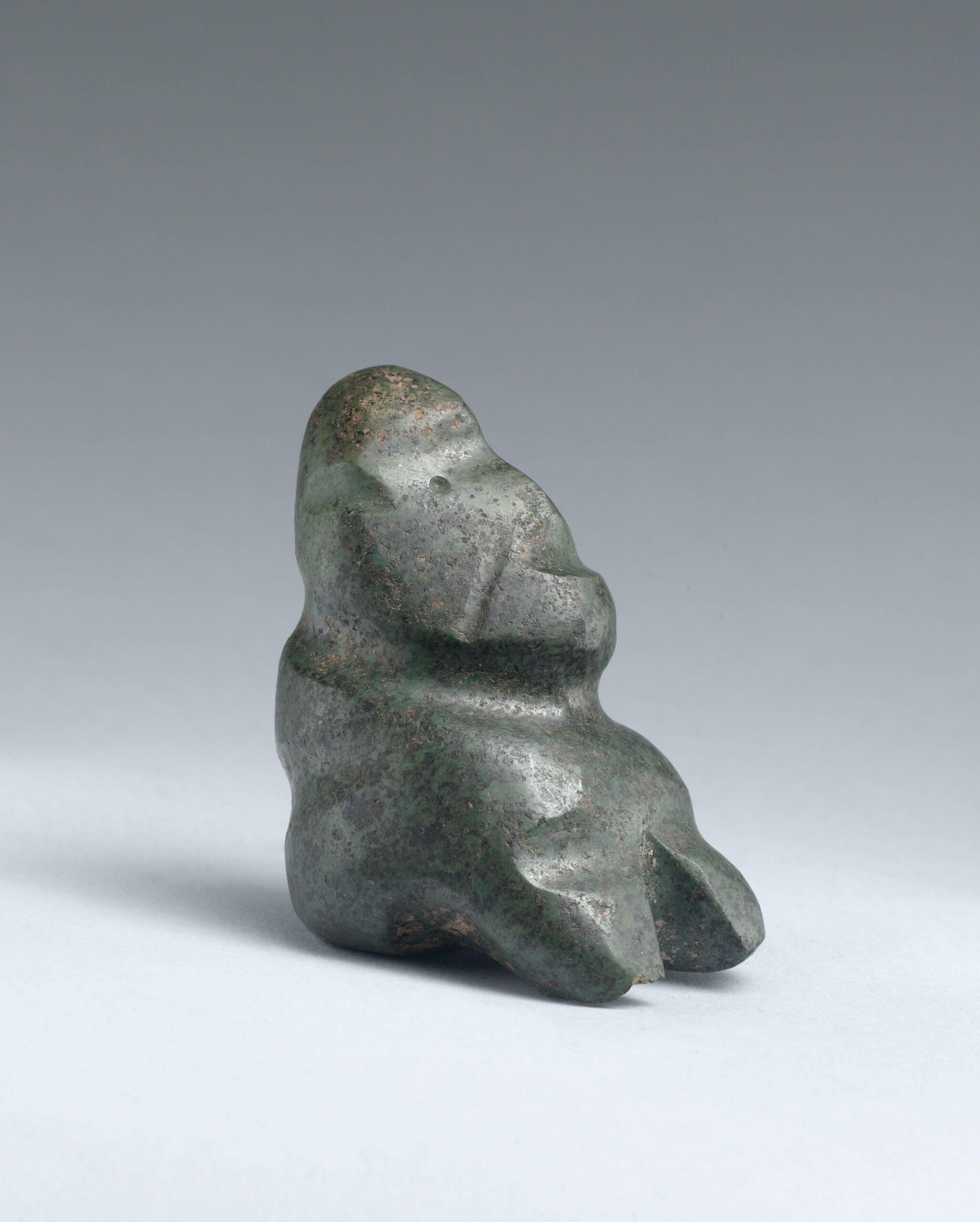 Stone in a rounded abstract form meant to depict a seated figure.