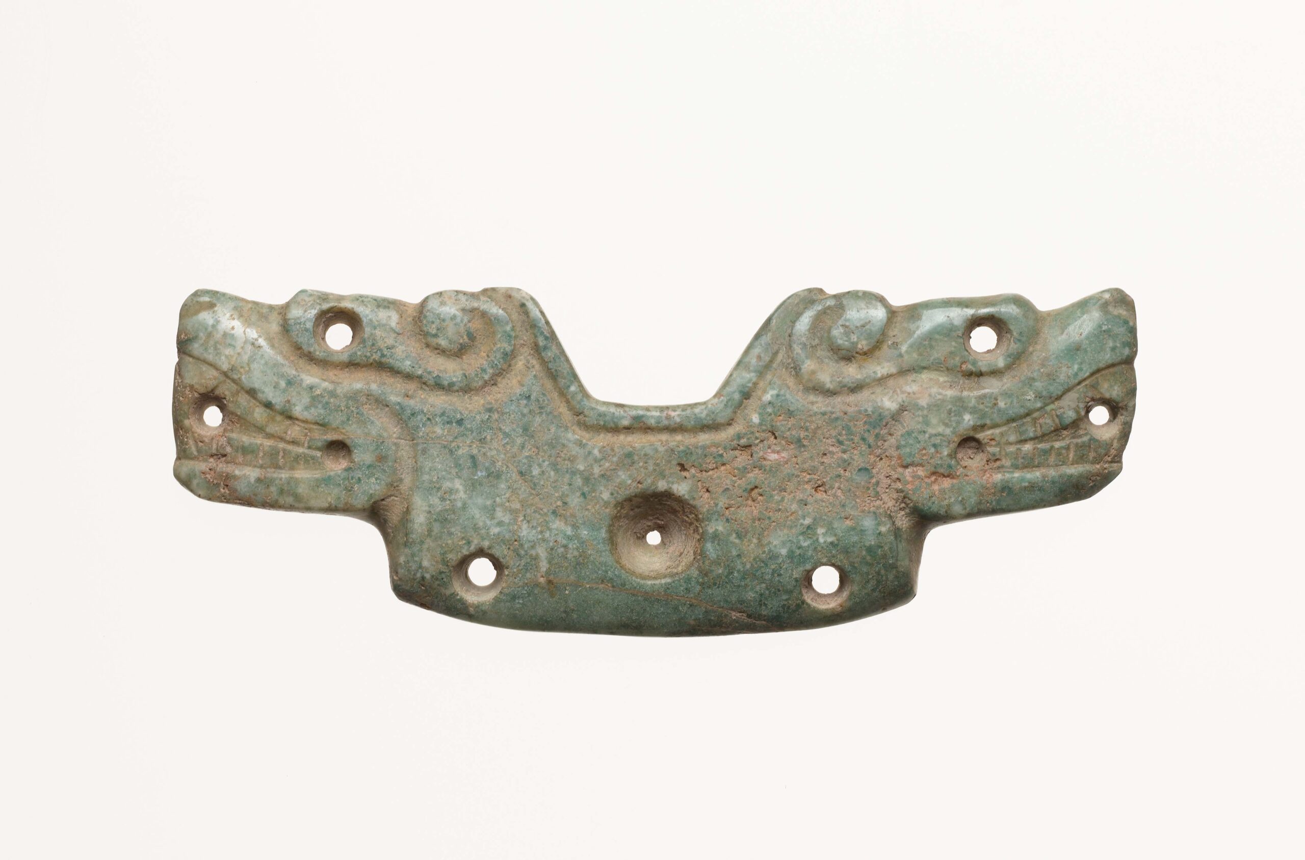 Pendant carved with two stylized alligators' heads facing away from each other.