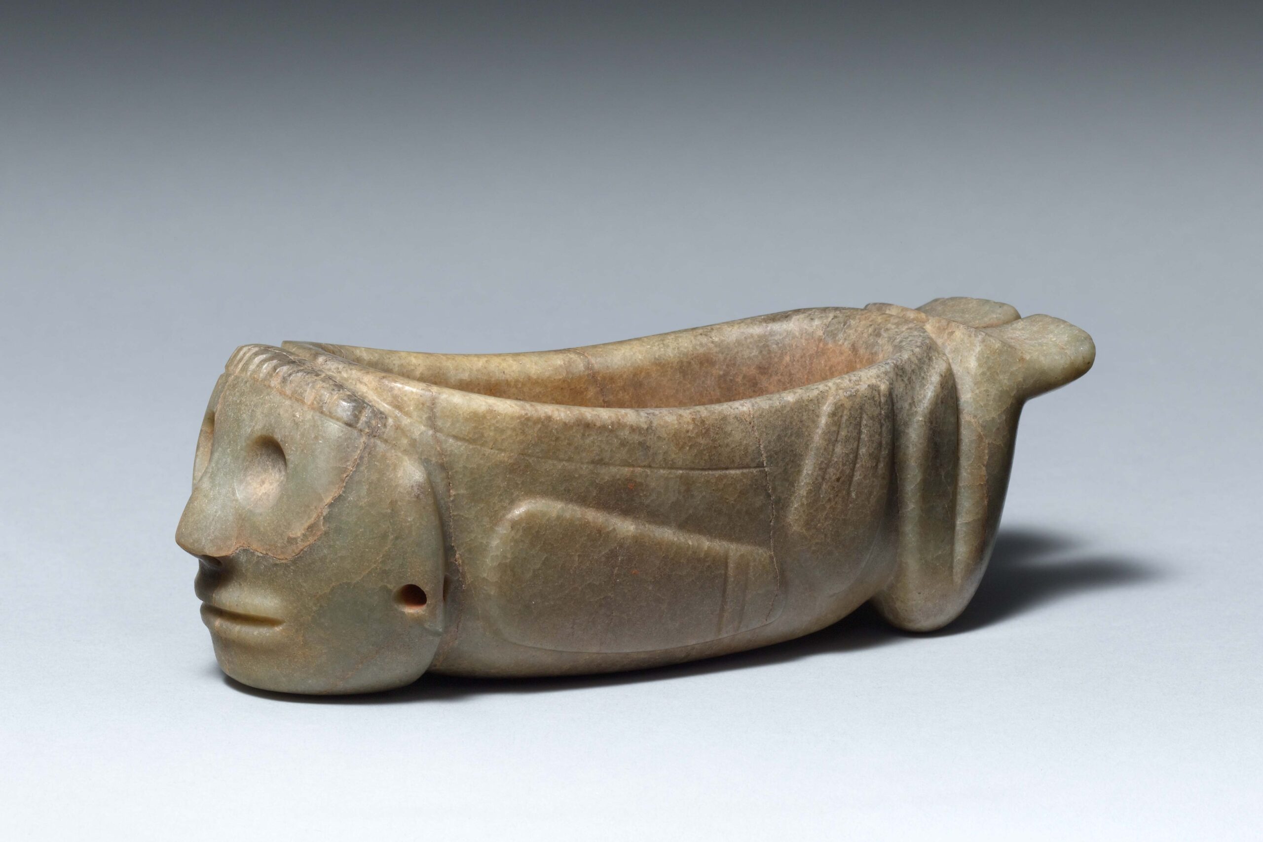 A jade bowl, carved to indicate a human figurelying on their stomach with legs extended backwards.