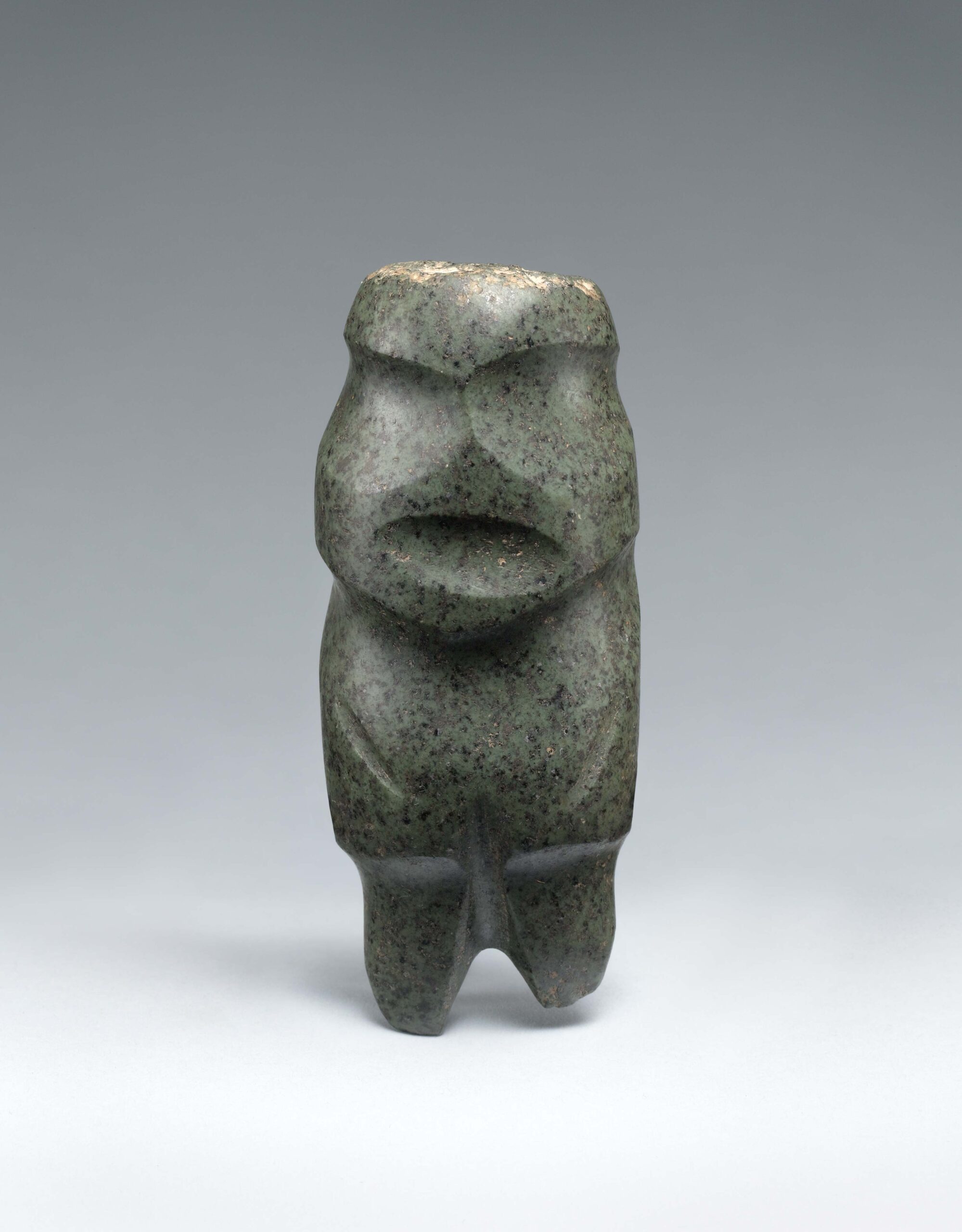 Abstract stone sculpture of a standing figure with indentations indicating facial features and arms at torso.