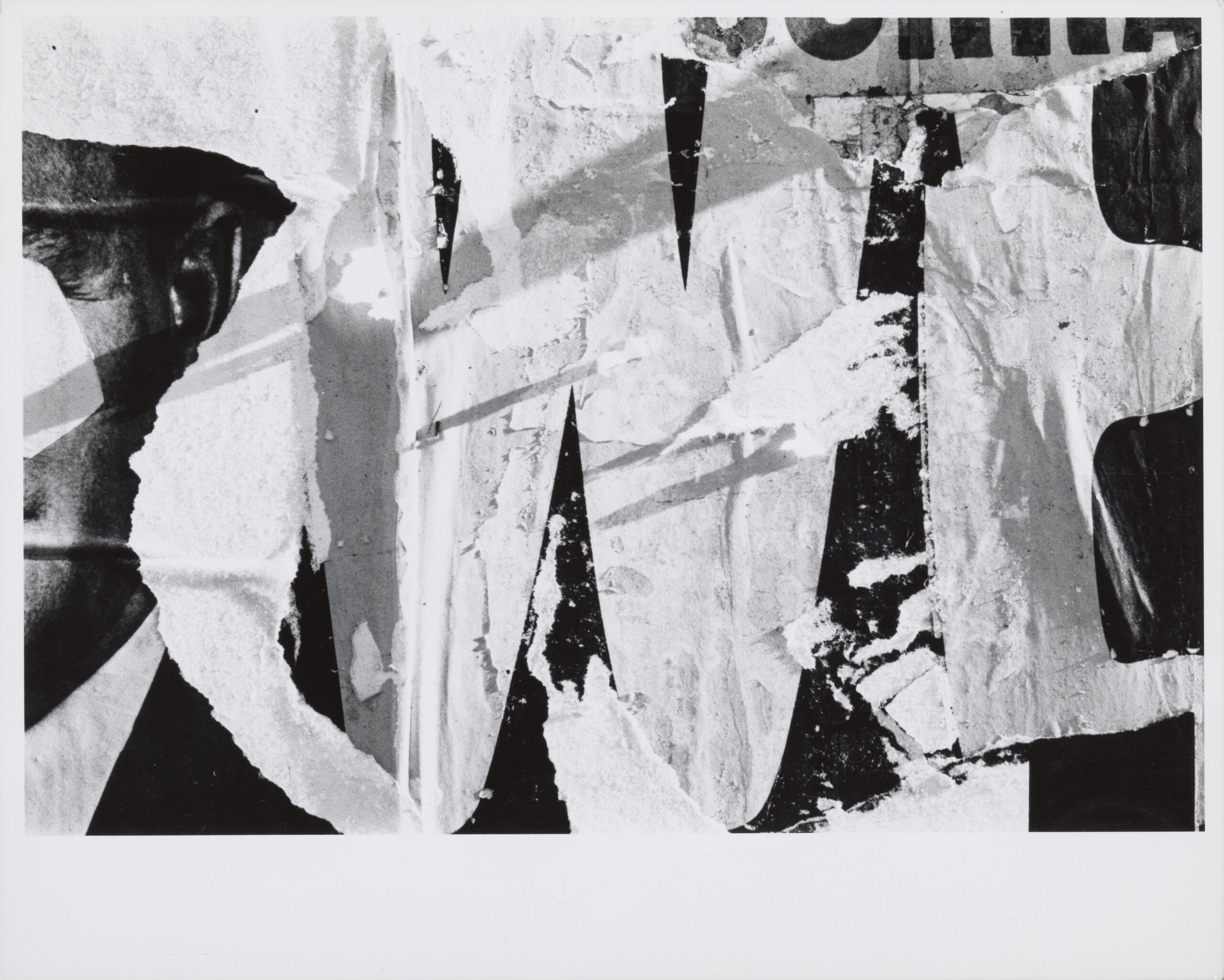 Black and white photograph of weathered and torn advertisements.