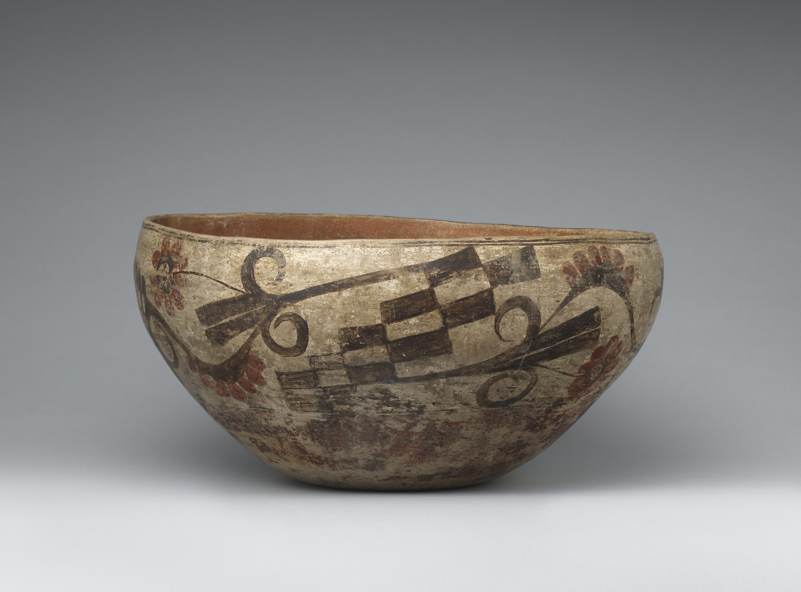 An Acoma bowl with checkered design and floral patterns in brown and red.