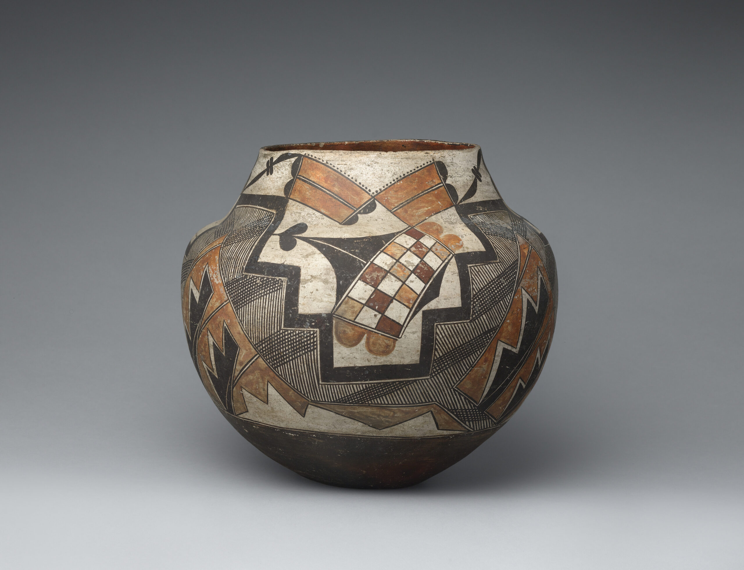 A four-color olla decorated with geometric shapes and checkered designs.