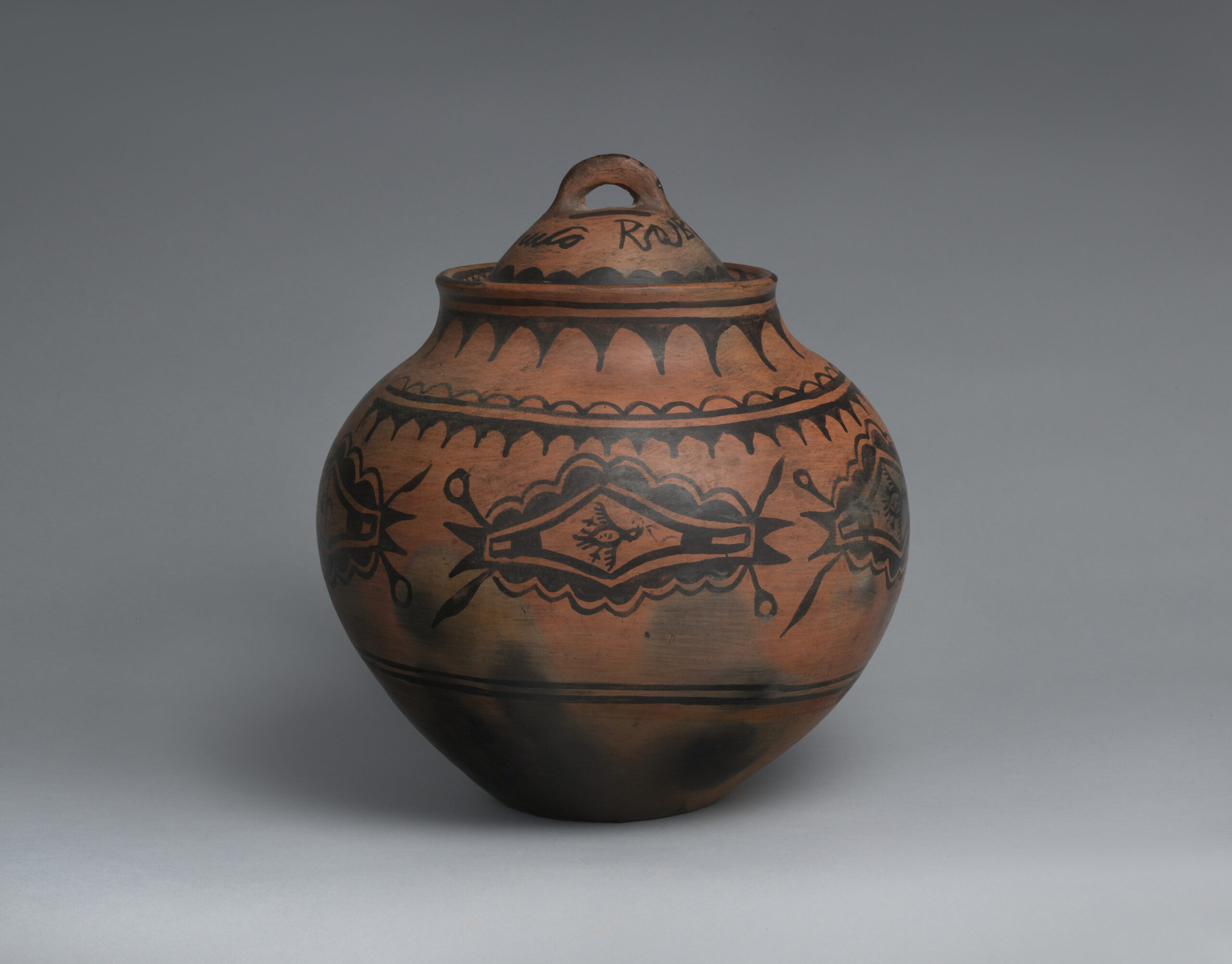 A San Ildefonso red lidded jar with black designs.