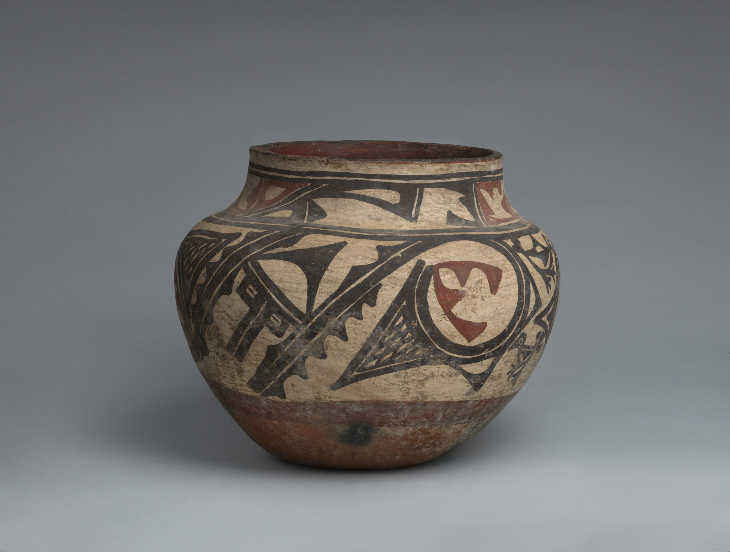A Zia jar with two bands of abstract geometric designs in black and rust.