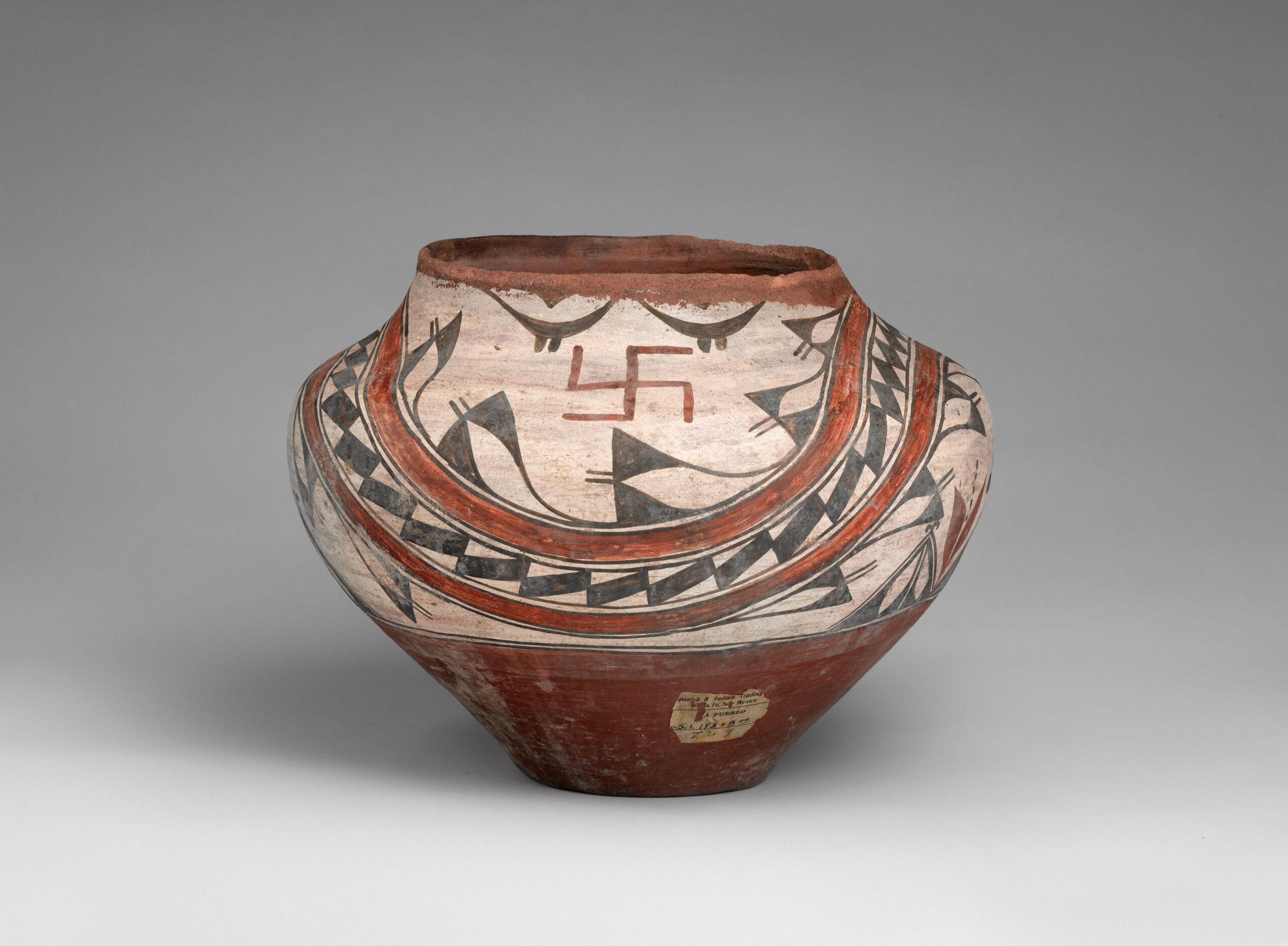 A Zia olla with an abstract design and two whirling log symbols painted in beige, brown, and black.
