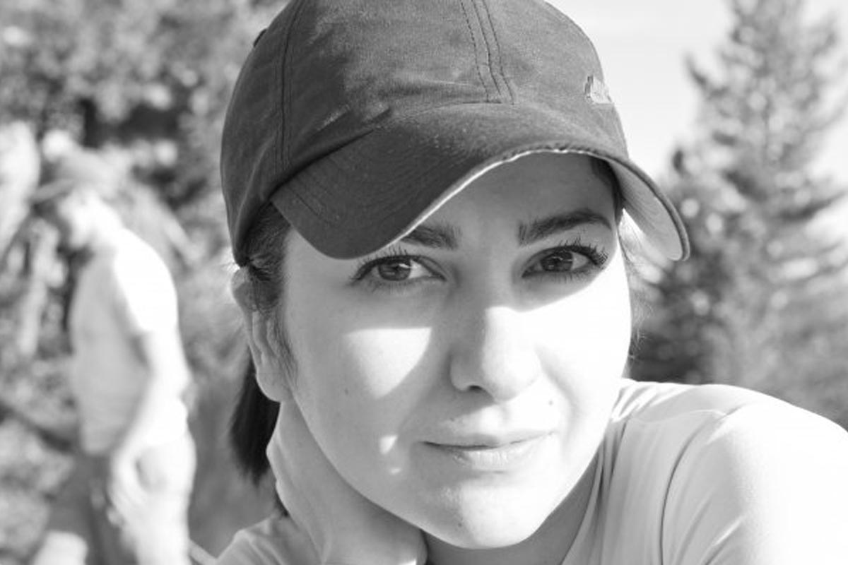 A black and white portrait of Yasaman Hashemian wearing a baseball hat outdoors.