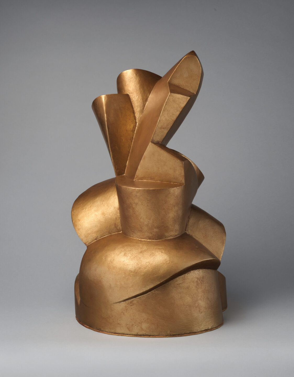 Gold sculpture of broad, cylindrical and flat-edged forms including a spiral.