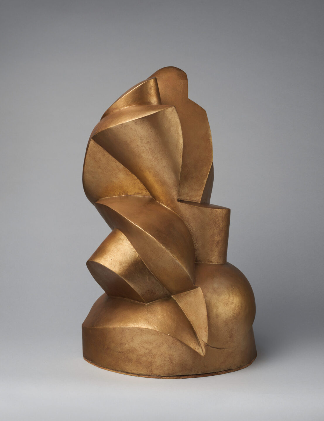 Gold sculpture of broad, cylindrical and flat-edged forms including a spiral.
