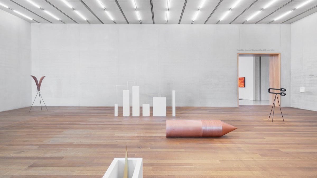 A wide shot of a white-walled gallery with five stand-alone art pieces dispersed throughout the space.