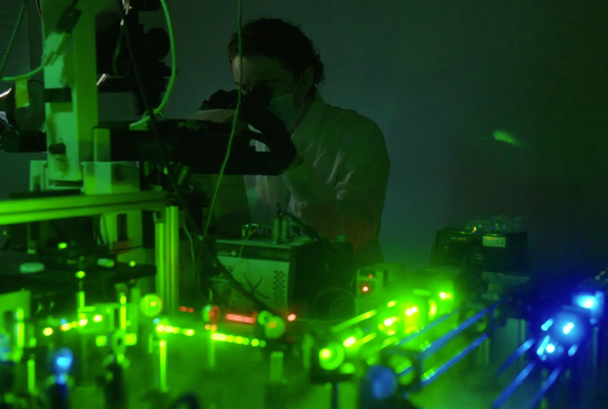 A researcher works with green and blue lasers in the Cissé Lab at MIT.