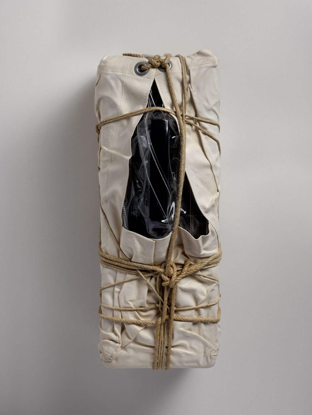 Photograph of a payphone wrapped in sackcloth with rope and twine.