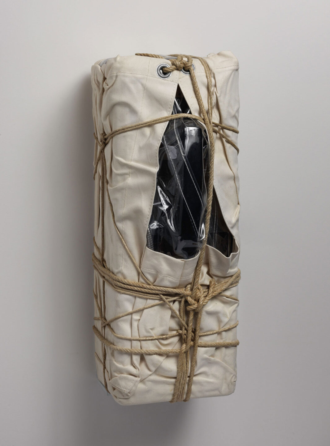 Side view of a payphone wrapped in sackcloth with rope and twine.