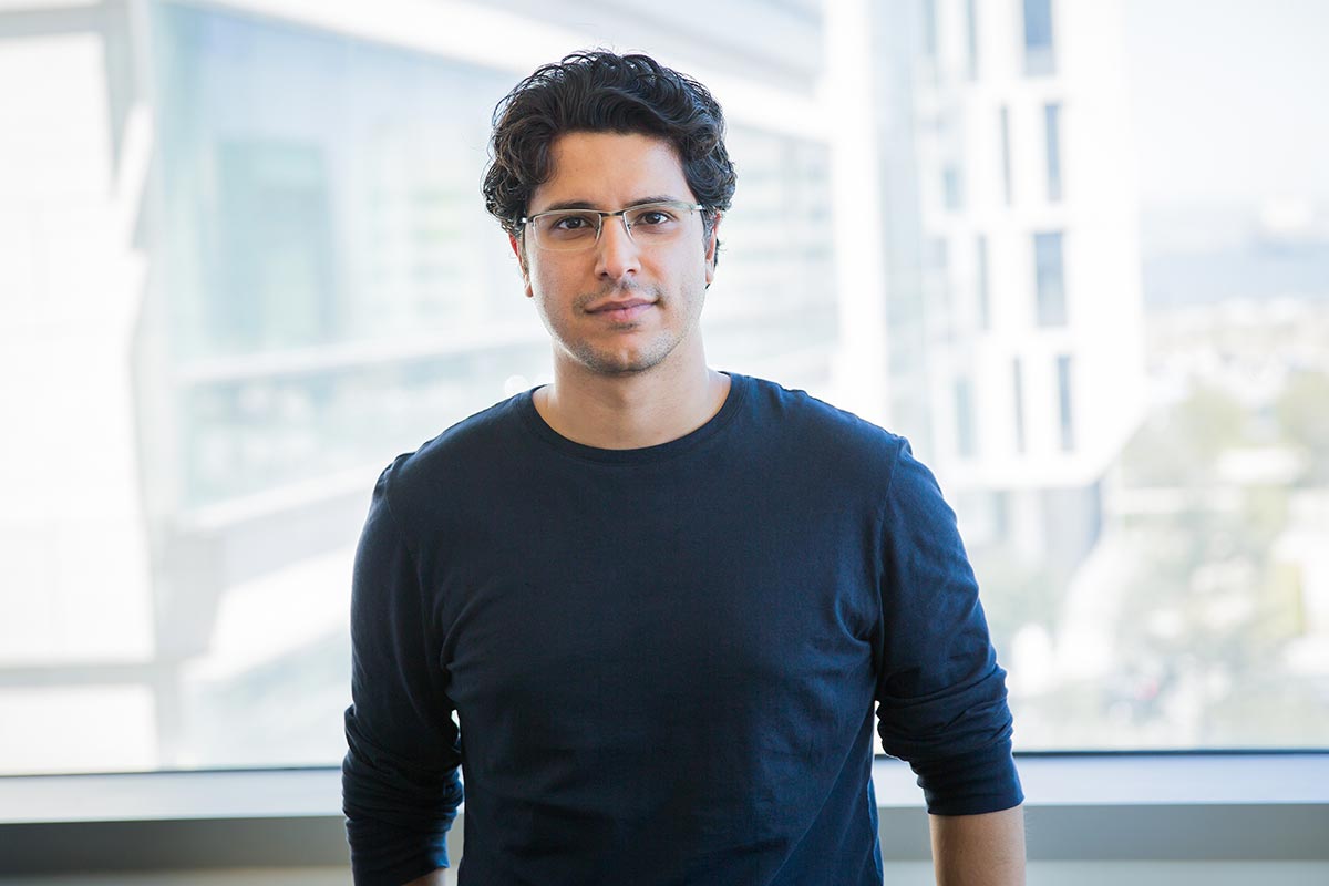 Hani Goodarzi standing in front of a wall fo windows.
