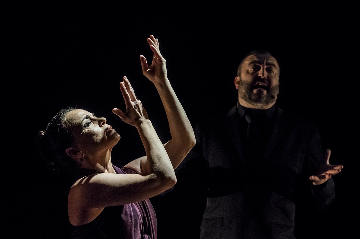 Soledad Barrio, arms raised in air, performs flamenco while a musician sings in the background.