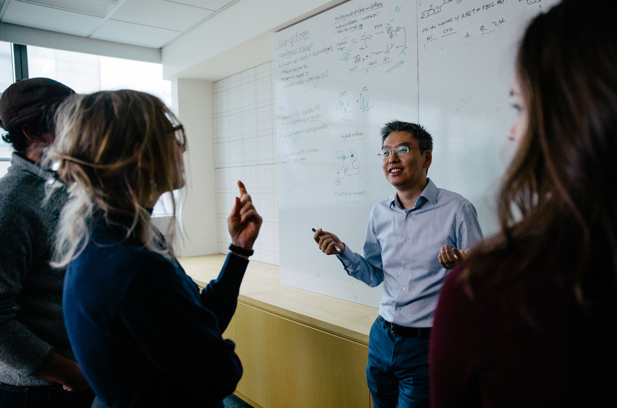 Harris Wang talking with colleagues in front of a white board.
