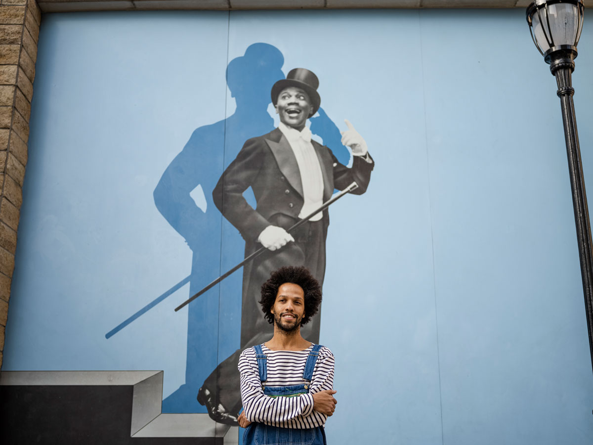 Leonardo Sandoval in front of mural of Bill "Bojangles" Robinson.