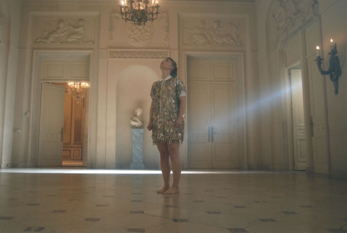 Alice Gosti standing in the Marica Vilcek Great Hall with a light beam behind her.