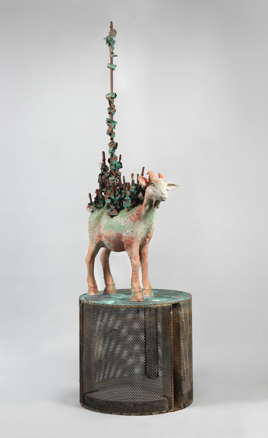 A cast bronze sculpture of a goat on top of a washing machine drum.