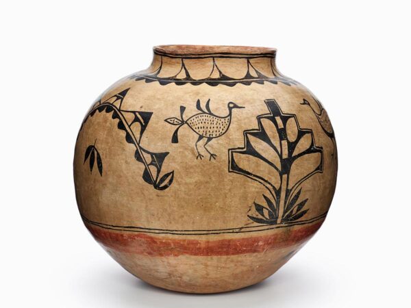 A brown Cochiti jar painted with a black design including leaves, a plant, and four birds.