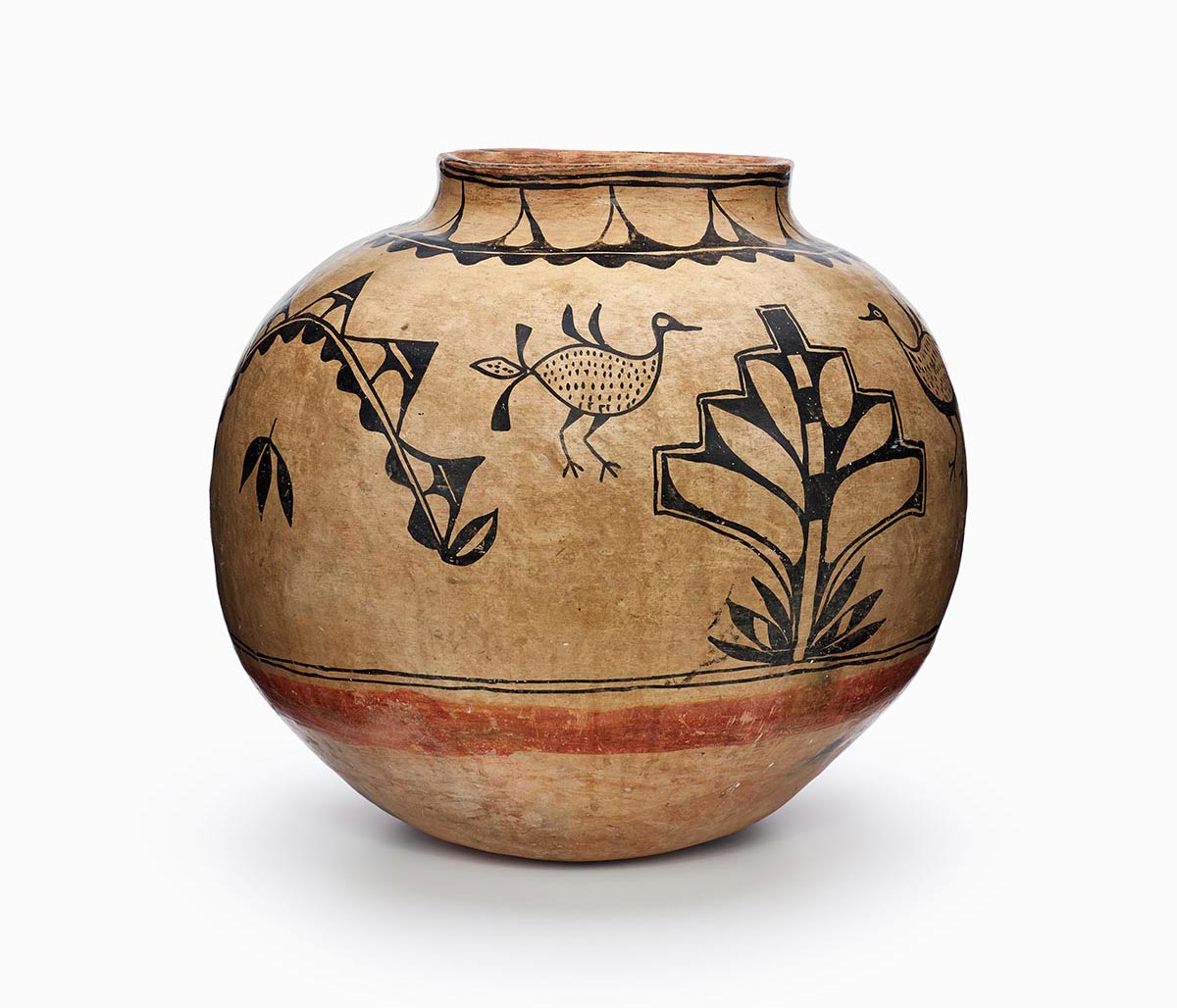 A brown Cochiti jar painted with a black design including leaves, a plant, and four birds.