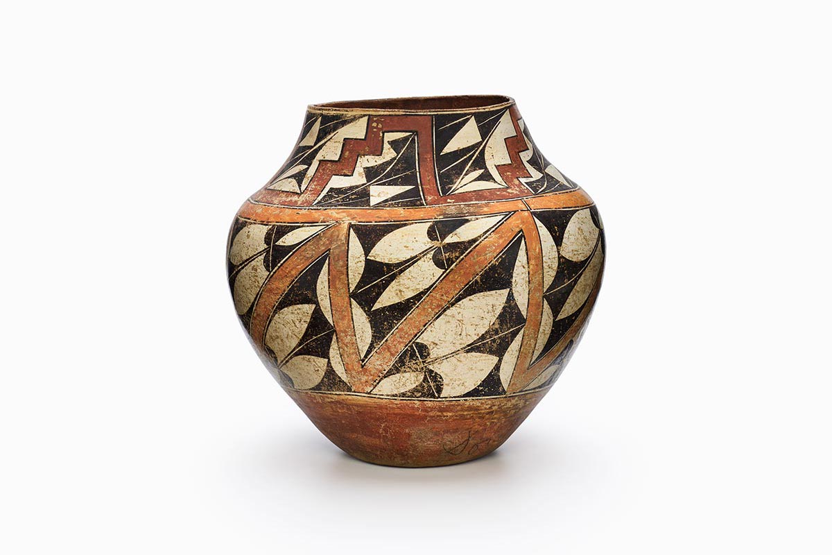 An Acoma pot decorated in white, red, orange, and black geometric shapes.
