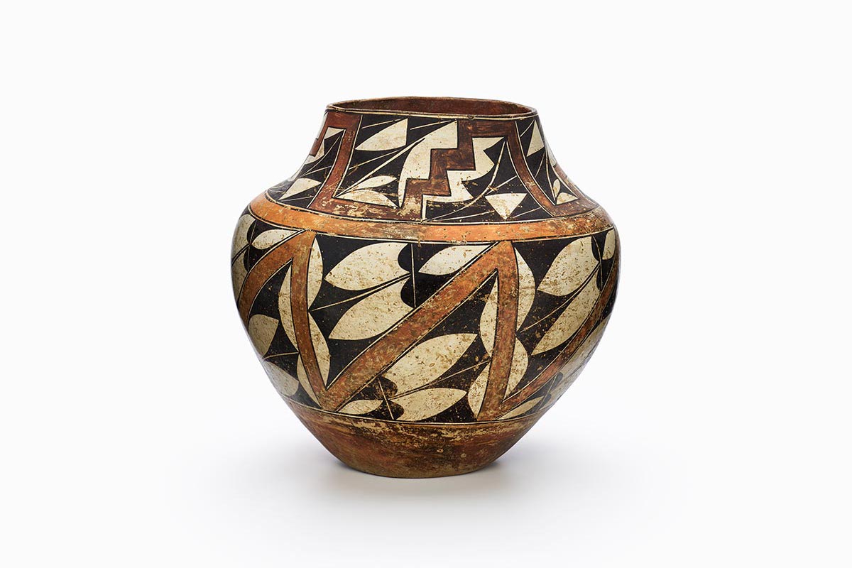 An Acoma jar with zigzagging and horizontal orange and red rainbow bands.