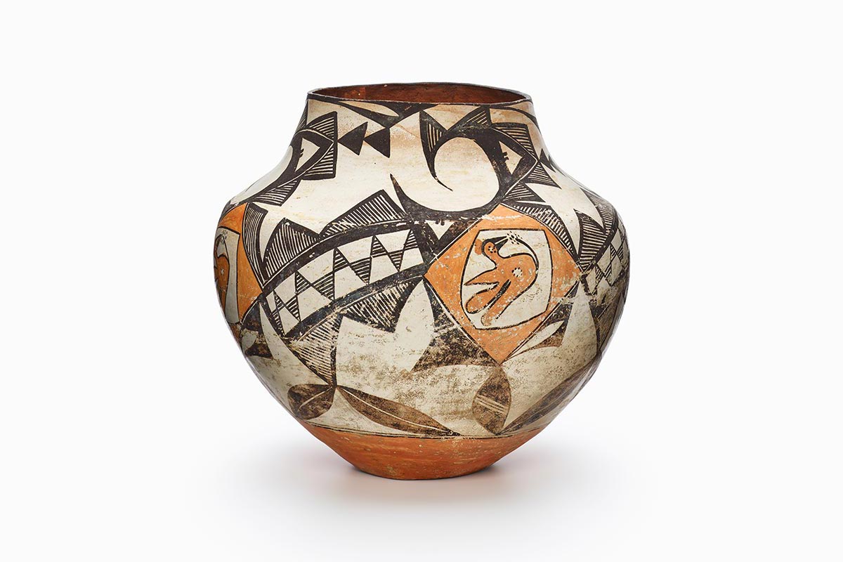 A three-color Acoma polychrome jar featuring white slip with black and orange painted decoration.