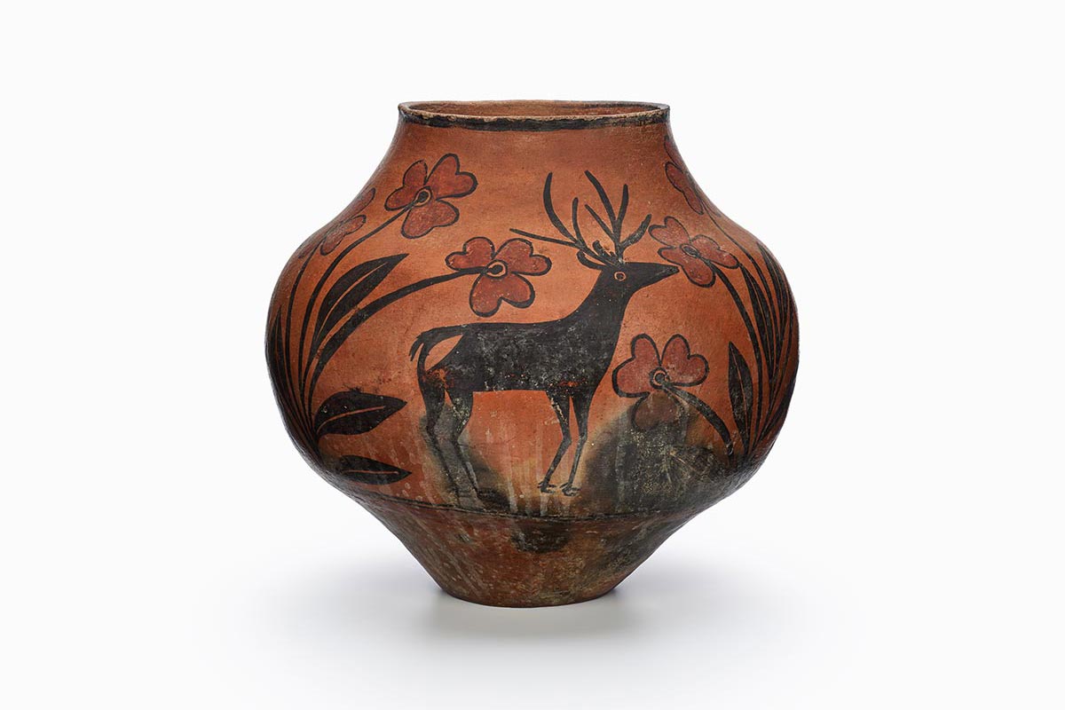 A Zia water jar with a black deer that is grazing among red flowers and leaves.