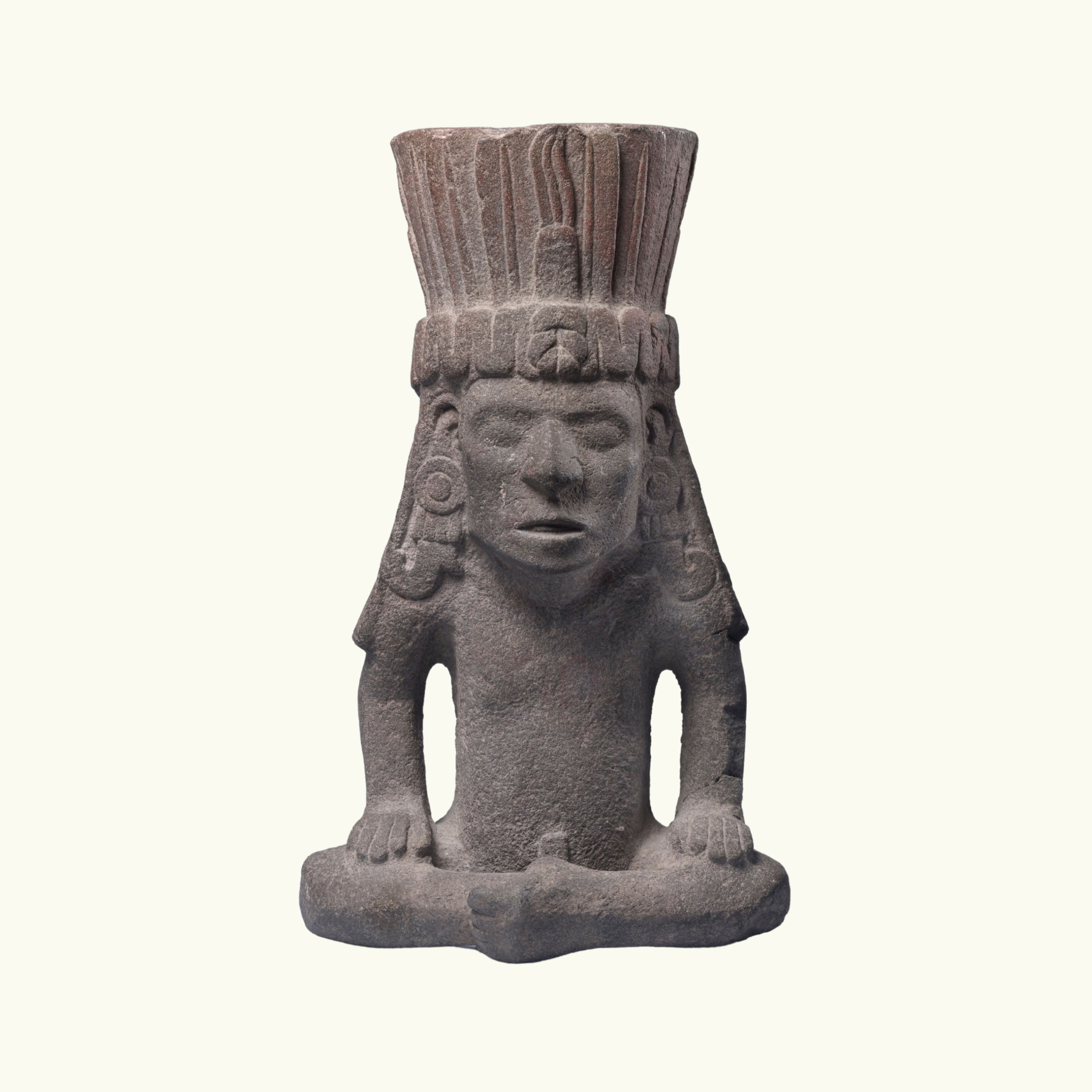 A seated volcanic stone figure with a headdress.