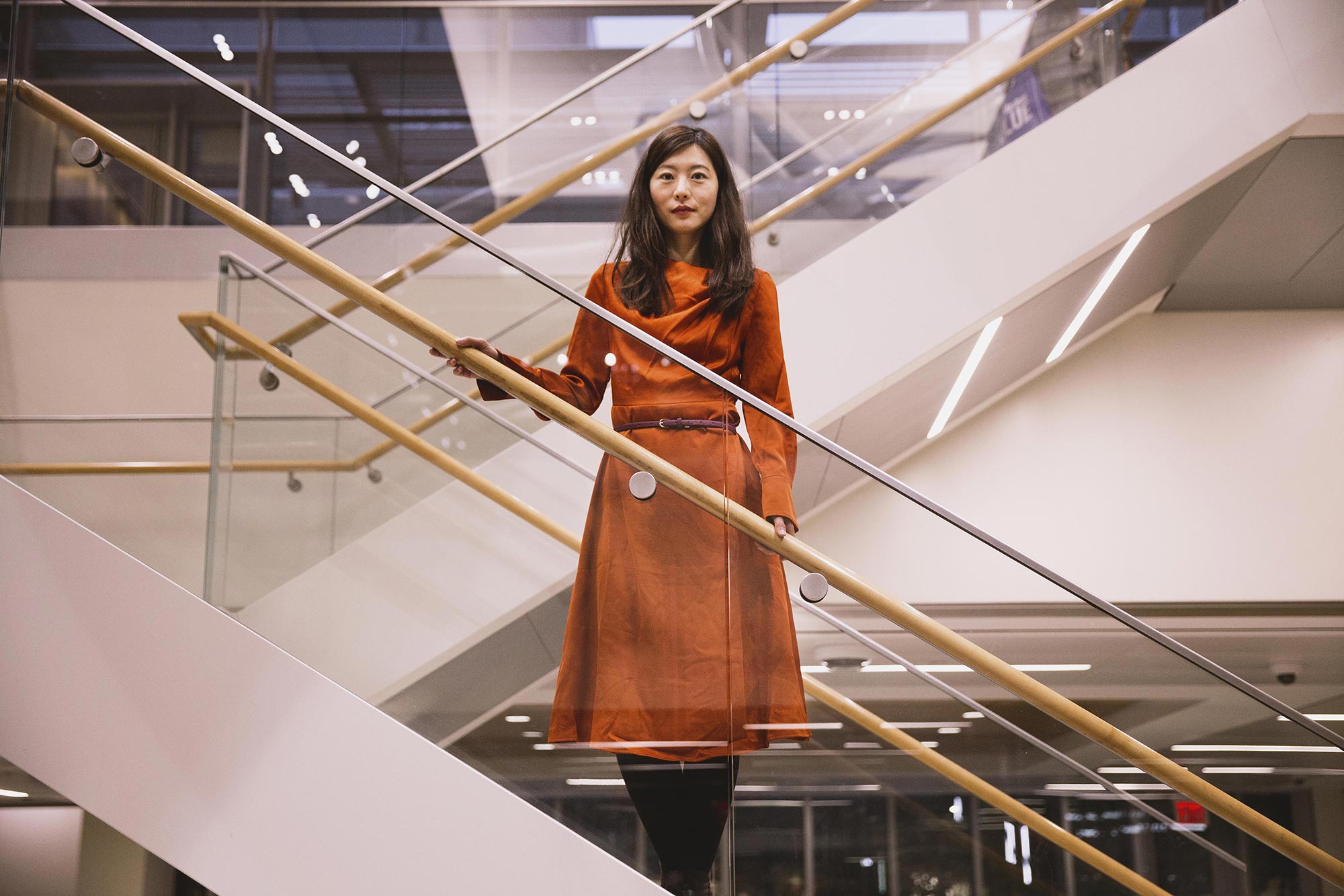 Biyu He in a red dress standing on an open stairwell.