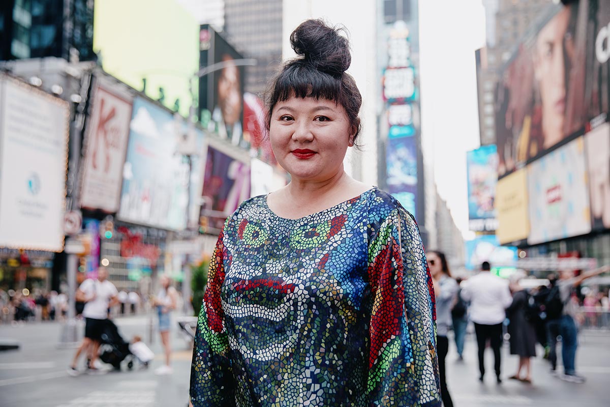 Du Yun stands in Times Square wearing a colorful dress.