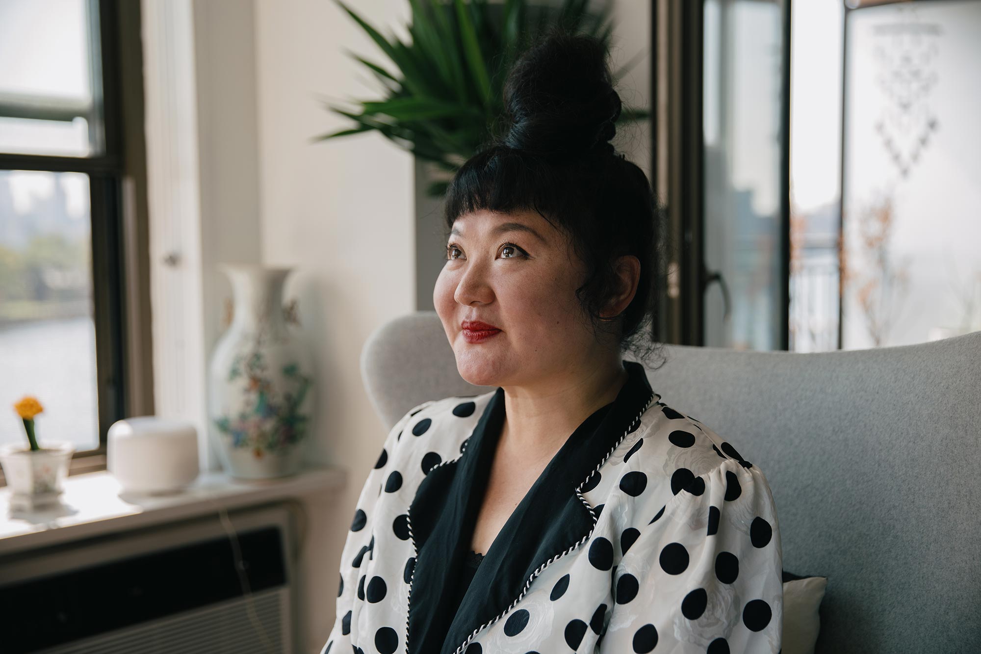 Du Yun in a white and black blazer, sitting on a chair.