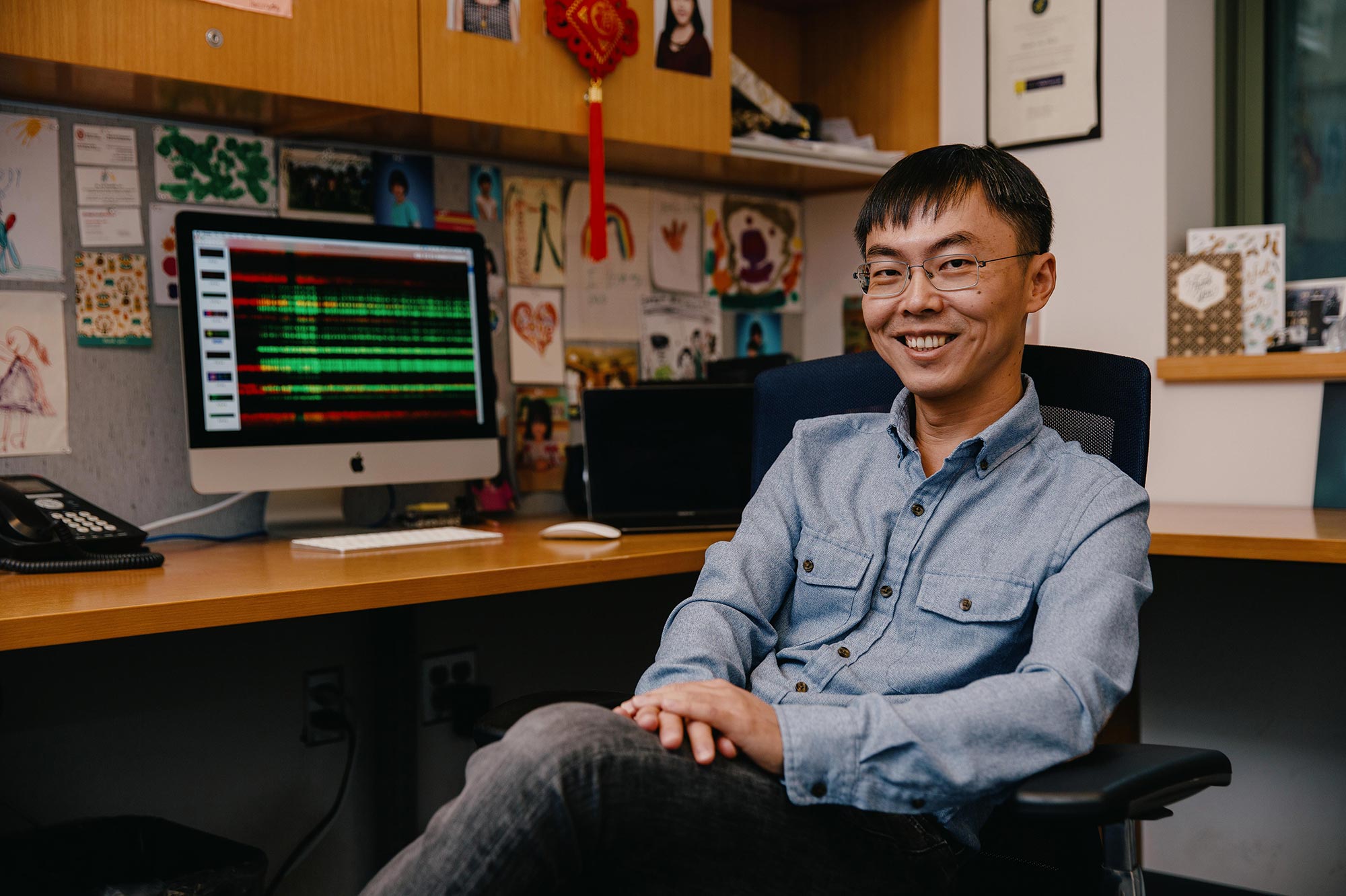 Shixin Liu seated in his office, hands folded on his leg.