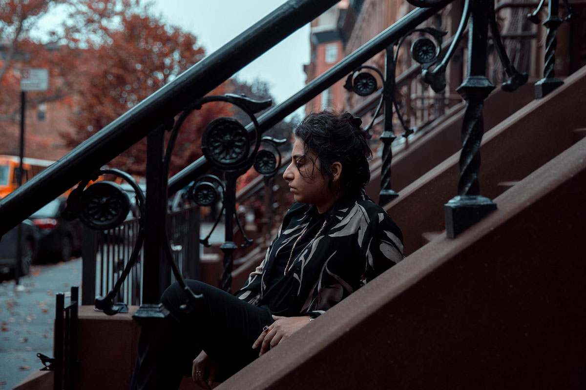 Arooj Aftab sitting on the steps of outside a building in Brooklyn, NY.